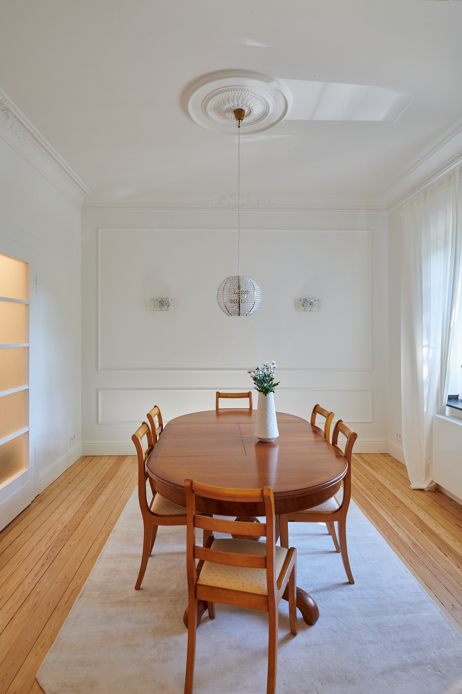 Rosetón decorativo y molduras que realzan el elegante comedor con lámparas colgantes.
